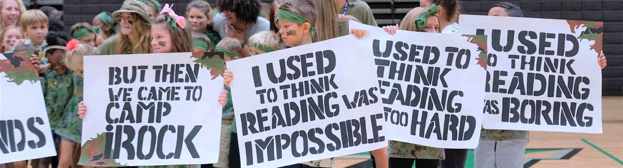 camp irock campers hold signs which say i used to think reading was impossible but then i came to camp irock