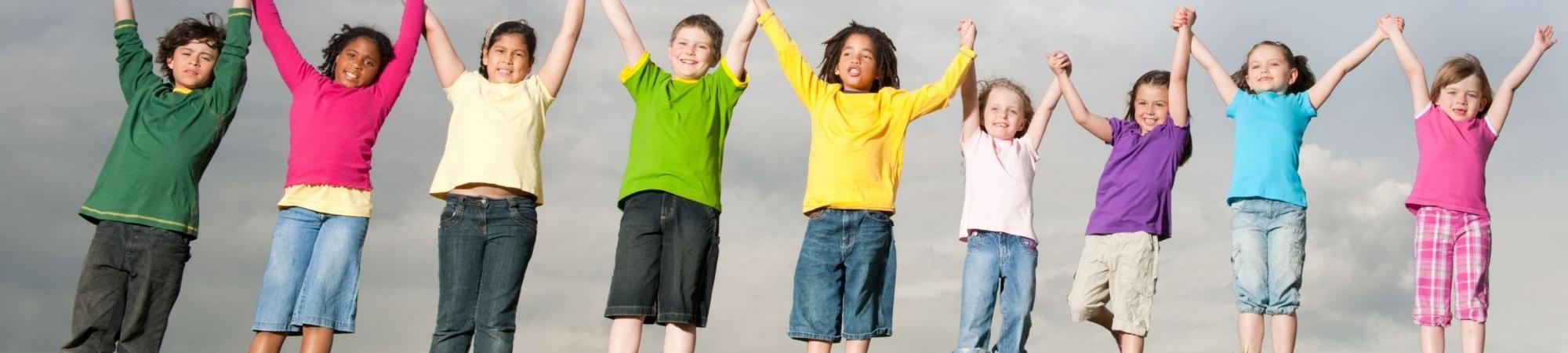 Children raising their arms in front of storm clouds