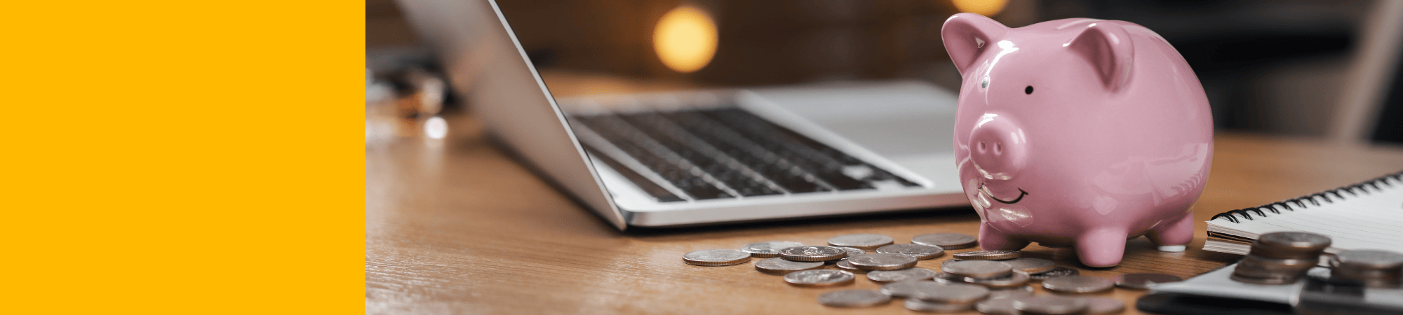 a piggy bank on a desk with a laptop and coins