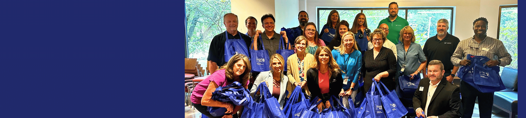 group of volunteers posing for the camera holding United Way of Pickens County tote bags they have just stuffed with literacy kits