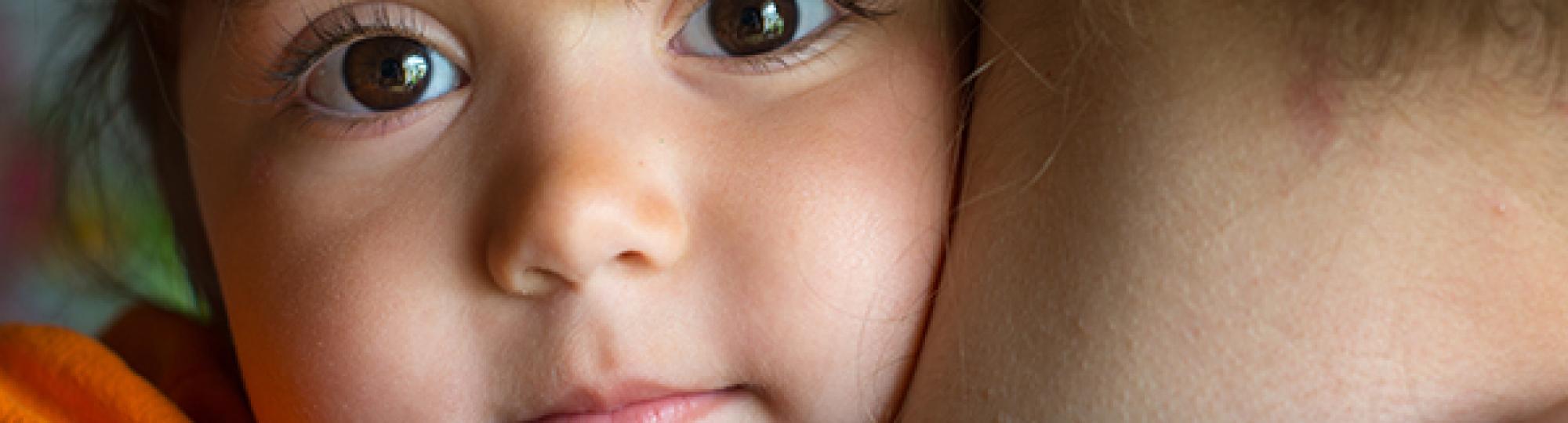 child looking over mothers shoulder