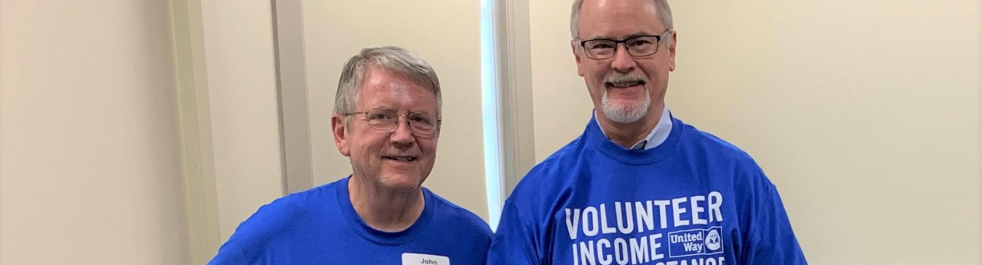 Two male tax volunteers pose in VITA tshirts