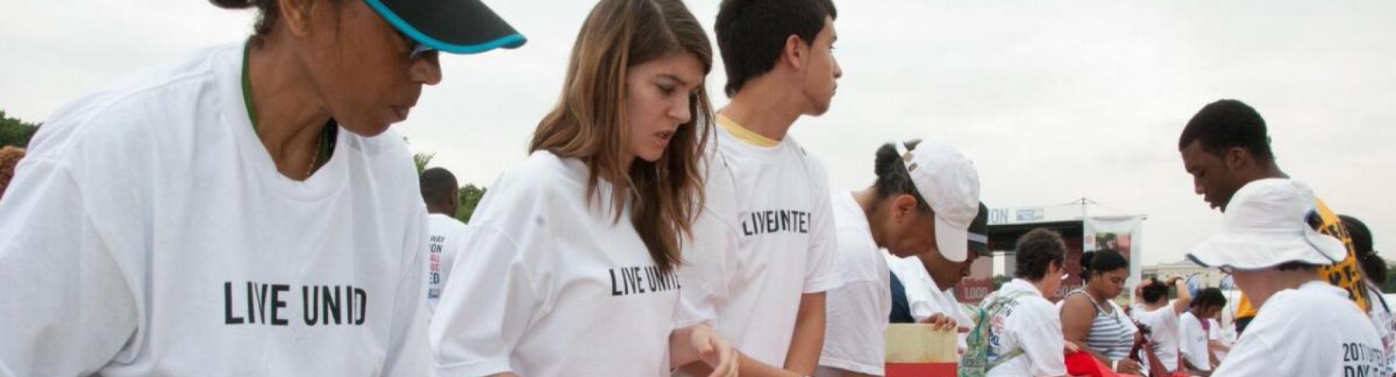 People wearing Live United tshirts stuffing books into bags