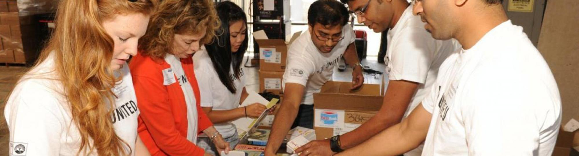 volunteers wear LIVE UNITED tshirts on eaither side of a table sorting books