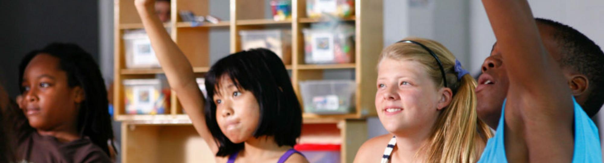 children in a classroom raising hands