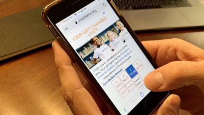 Person holding a phone opened to the donation page