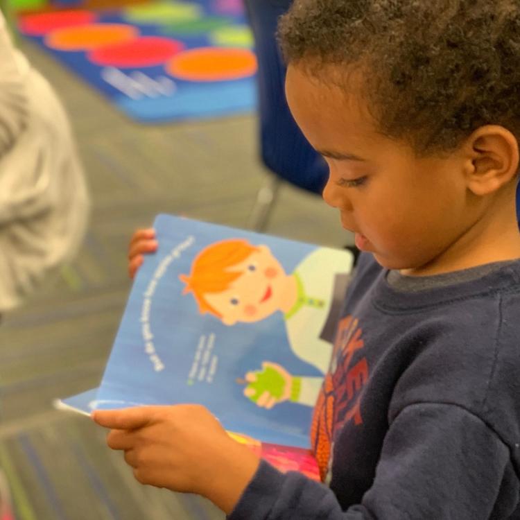 A toddler boy holds a Preschool Pages book