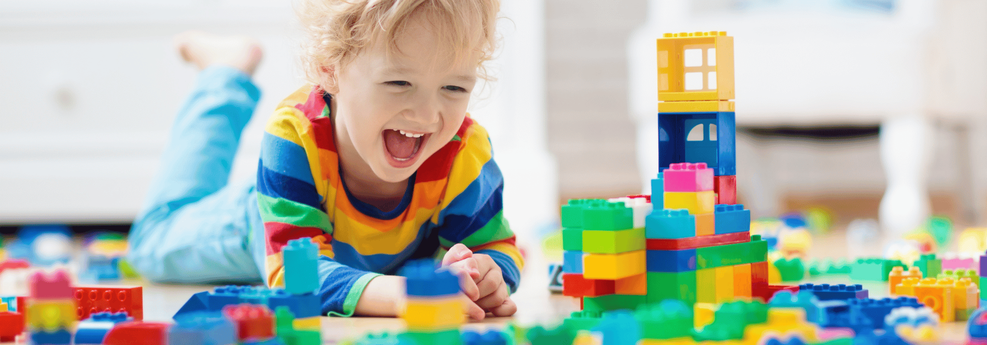 smiling child playing with blocks on the floor