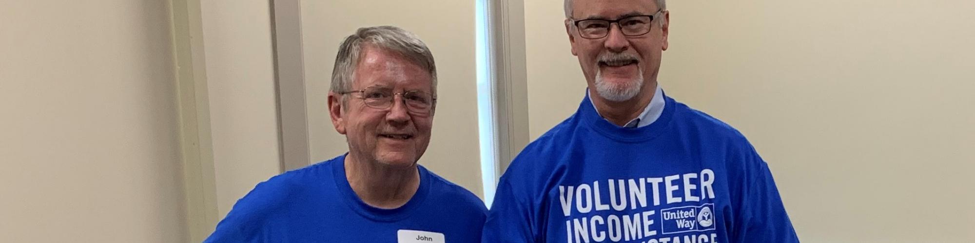 Two male tax volunteers pose in VITA tshirts