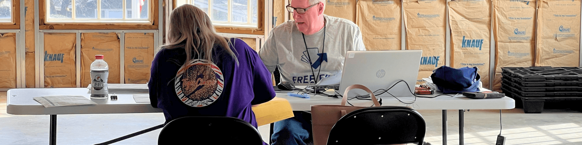 A Free File volunteer sits at a computer across the table from a client receiving free tax assistance.
