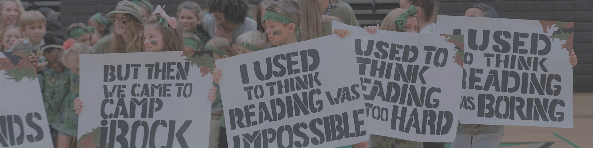 Camp iRock campers hold up signs that say I used to think reading was boring, hard and impossible but then we came to camp irock