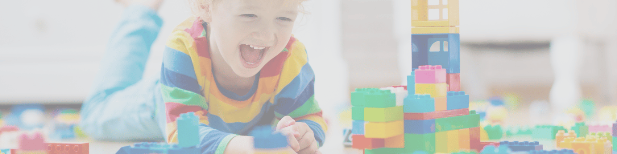 a smiling child plays with blocks on the floor