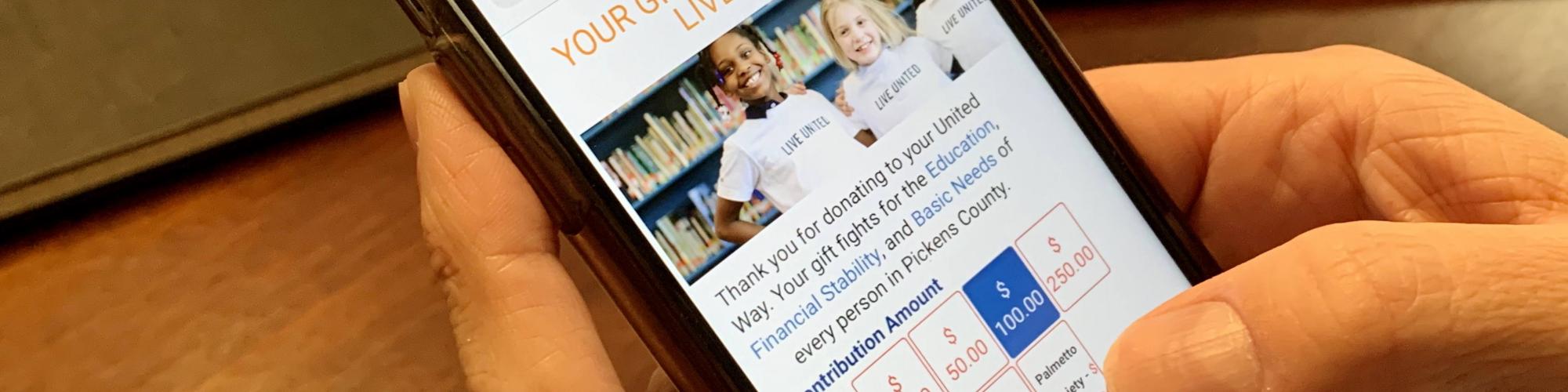 Person holding a phone opened to the donation page