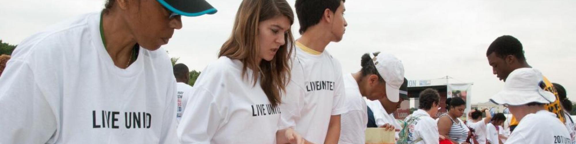 People wearing Live United tshirts stuffing books into bags