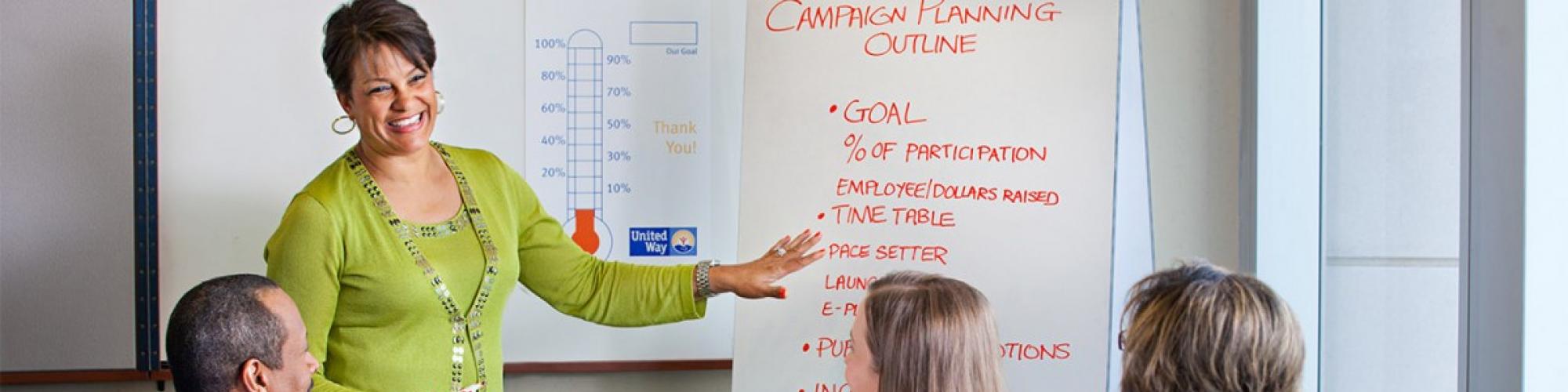 a woman points at a campaign timeline while talking to co-workers