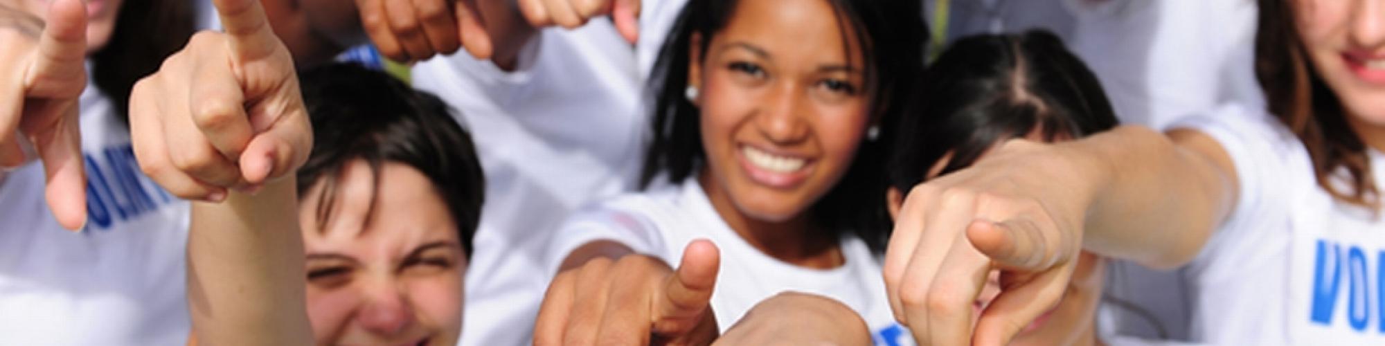 Group of people with VOLUNTEER tshirts pointing at YOU