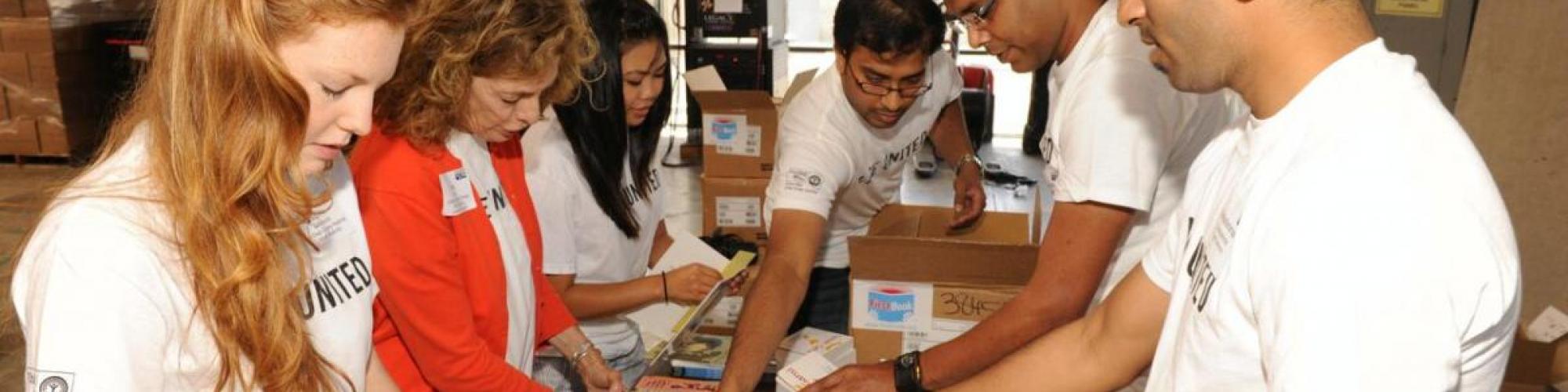 volunteers wear LIVE UNITED tshirts on eaither side of a table sorting books